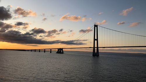 Bridge over calm sea against sky during sunset