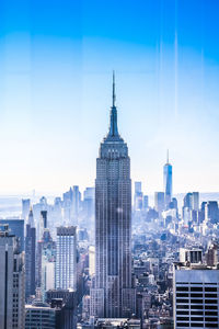 Empire state building and one world trade center seen through glass window in city