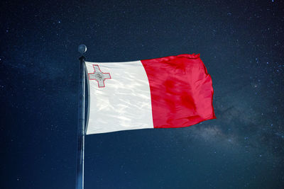 Low angle view of maltese flag against star field sky