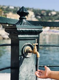 Close-up of hand on railing against river