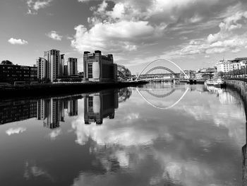 Bridge over river by buildings against sky in city