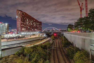 Railroad tracks in city against sky at night