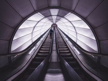 Rear view of man standing on escalator at subway station