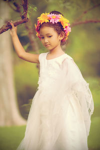 Low angle view of girl standing by flowering plant