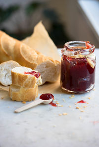 Close-up of baguette and strawberry jam on table