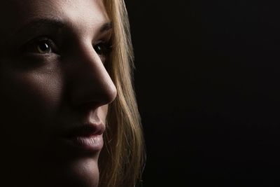 Close-up thoughtful woman against black background