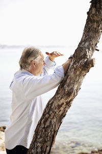 Senior man shielding eyes while looking at view