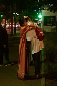 Friends standing on illuminated street at night