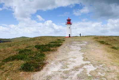 Lighthouse on field against sky