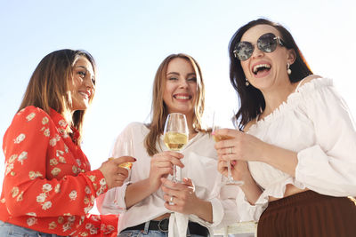 Smiling young woman drinking glasses outdoors