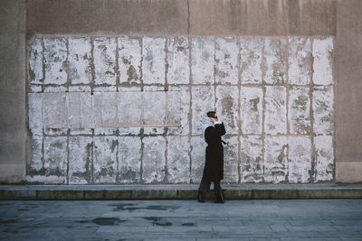 Full length of woman standing against wall outdoors