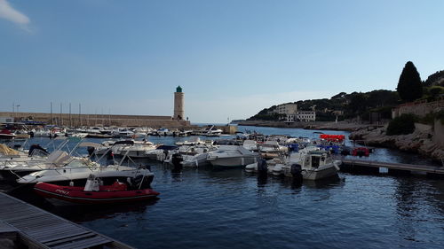 Boats moored in harbor against clear sky