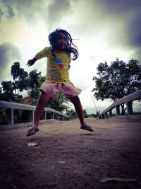 Full length of woman jumping against trees