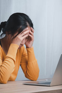 Midsection of woman using mobile phone while sitting on table