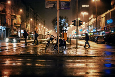 People and vehicles on illuminated city street at night