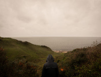 Rear view of man looking at sea against sky