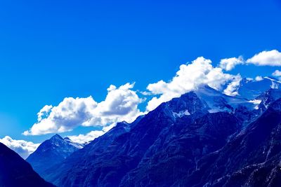 Scenic view of snowcapped mountains against blue sky