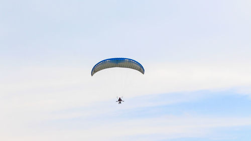 Low angle view of person paragliding against sky