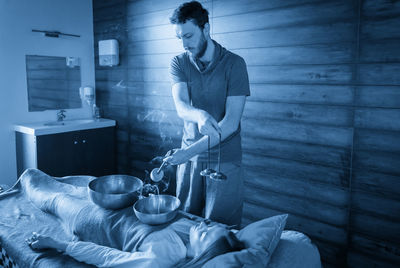 Side view of man sitting on bed at home