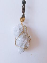 Close-up of crystal tied up over white background