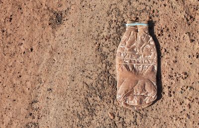 High angle view of weathered water bottle on sand