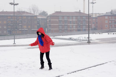 Full length of woman enjoying on snow covered field
