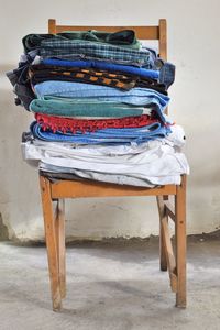 Stack of clothes on chair against wall