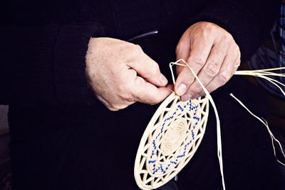 Midsection of man making wicker basket