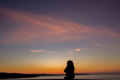 Silhouette woman standing by sea against sky during sunset