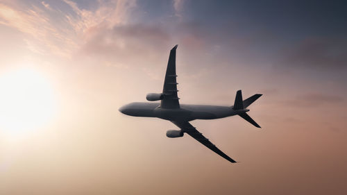 Low angle view of airplane flying against sky during sunset