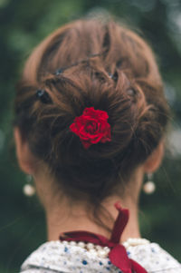 Red rose in hair bun of woman