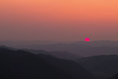 Scenic view of silhouette mountains against romantic sky at sunset