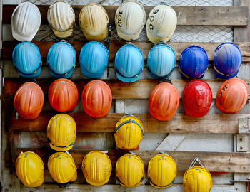 Multi colored helmets hanging on wooden wall