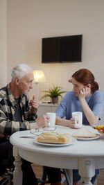 Side view of woman sitting on table at home