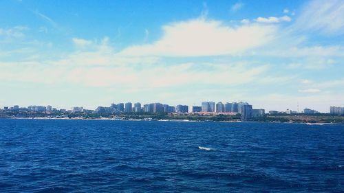 Sea by buildings in city against sky