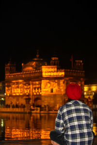 Rear view of a man in city lit up at night