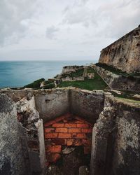 Stone wall by sea against sky