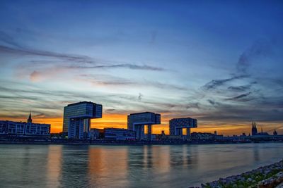 River by buildings against sky at sunset