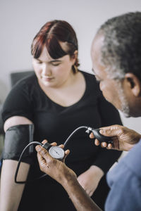 Male healthcare expert examining blood pressure of female patient in medical clinic