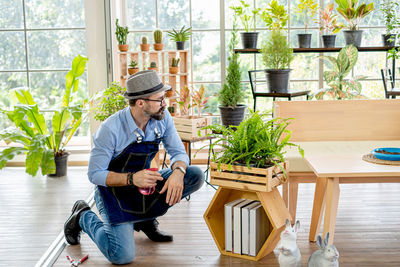 Full length of man sitting on chair in potted plant