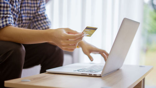 Midsection of man using laptop on table