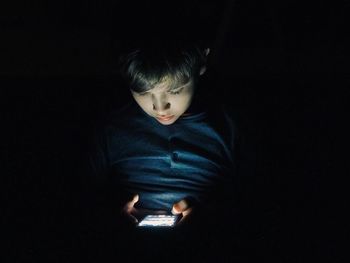 CLOSE-UP OF BOY IN ILLUMINATED DARKROOM