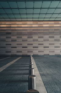 Bollards in row on road against wall