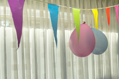 Close-up of balloons hanging against curtain