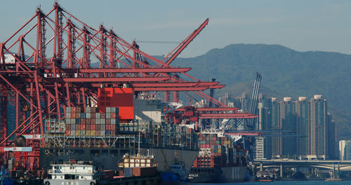 Cranes at commercial dock against sky