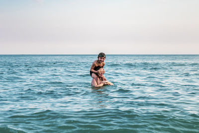 5 years old kid on top of his mother's shoulders, into the ocean
