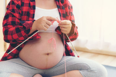 Midsection of woman holding while sitting at home