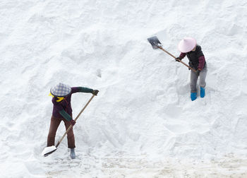 Full length of men cleaning snow with shovel