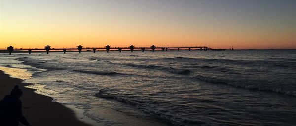 Scenic view of beach against clear sky during sunset