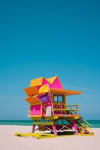 Colorful lifeguard hut on beach against clear blue sky